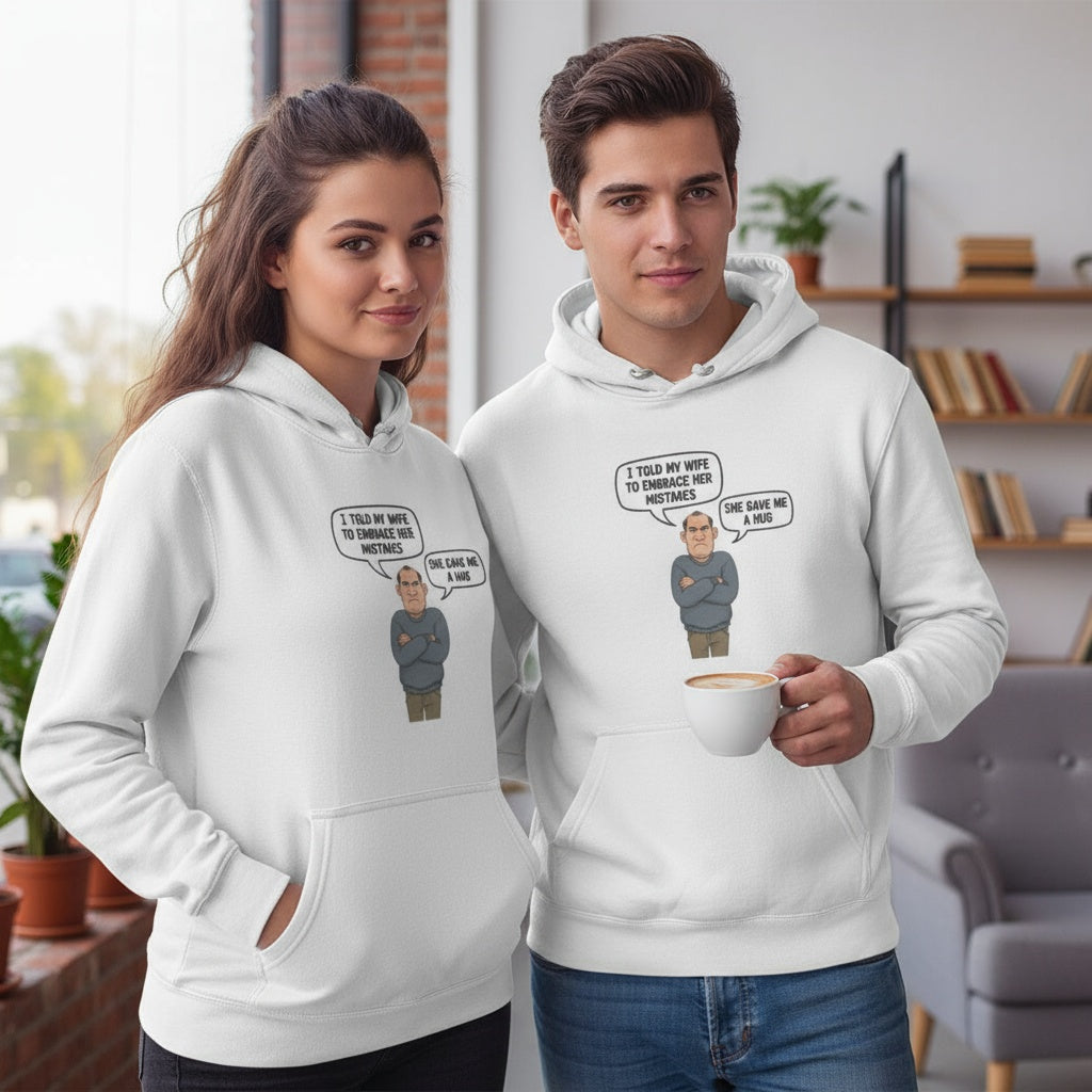 White fleece hoodie featuring a cartoon grumpy husband with the quote ‘I told my wife to embrace her mistakes. She gave me a hug.’ Funny, cheeky gift for men by Cheeky Tees Co.