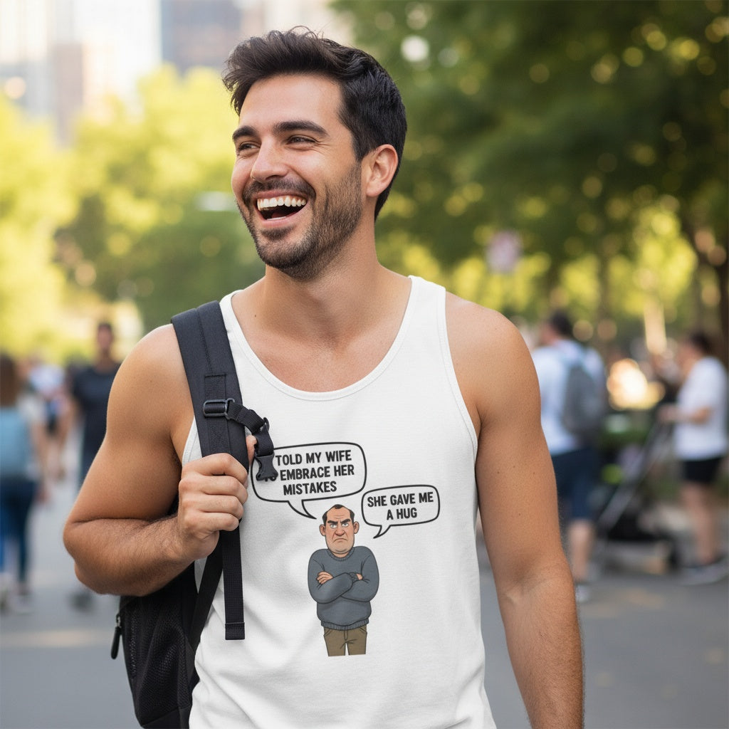 White unisex jersey tank top with a cartoon grumpy husband and the quote ‘I told my wife to embrace her mistakes. She gave me a hug.’ Funny, cheeky men’s tank by Cheeky Tee Co.